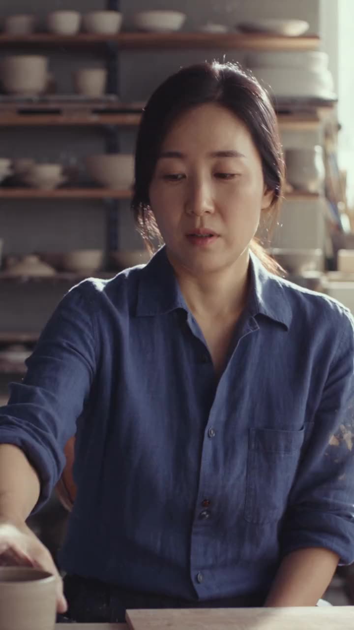 Ji-woo in her Busan workshop, clay dust on an indigo work shirt